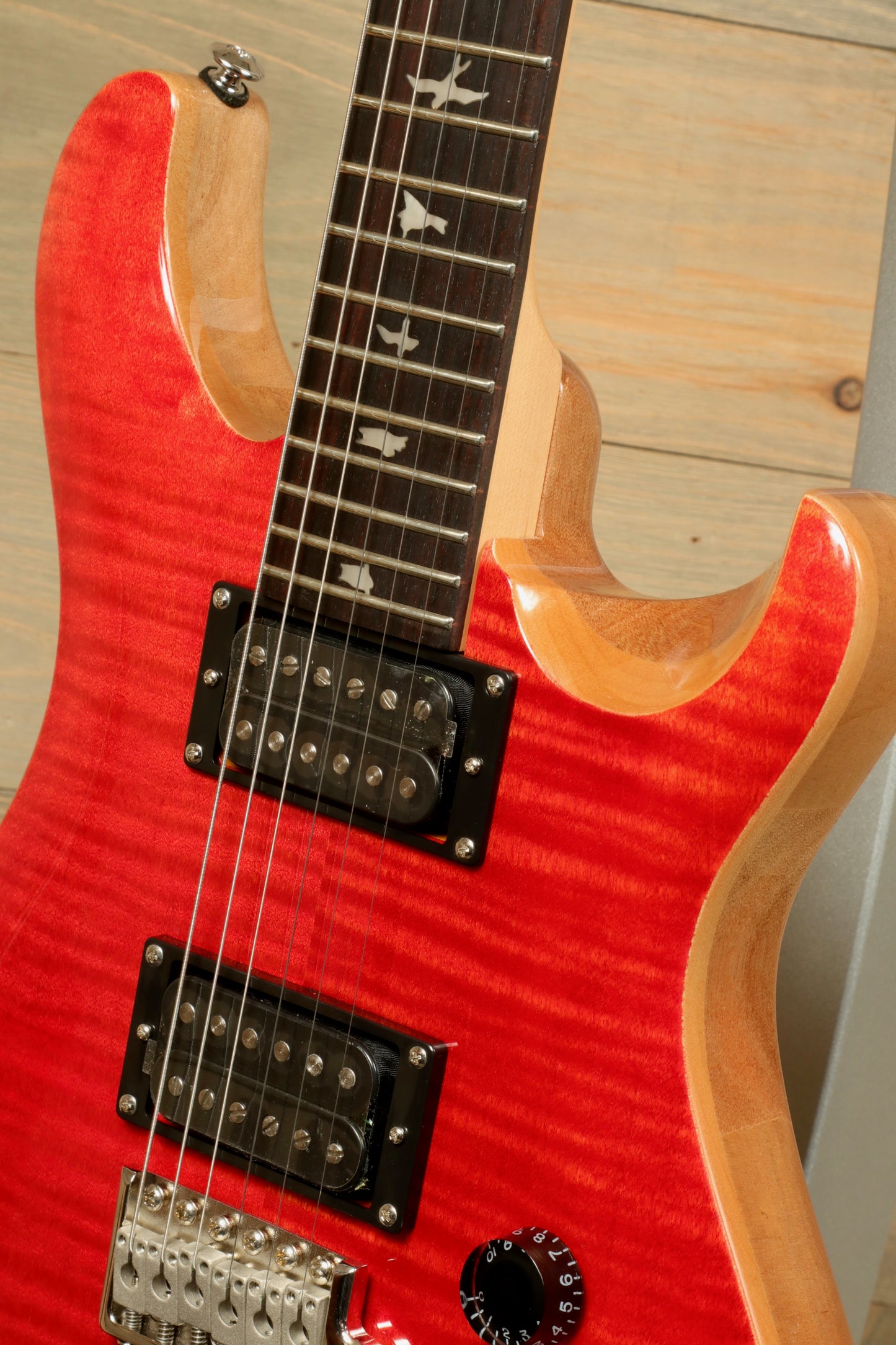 Close-up of PRS SE CE24 electric guitar featuring a vibrant red finish and dual humbucker pickups