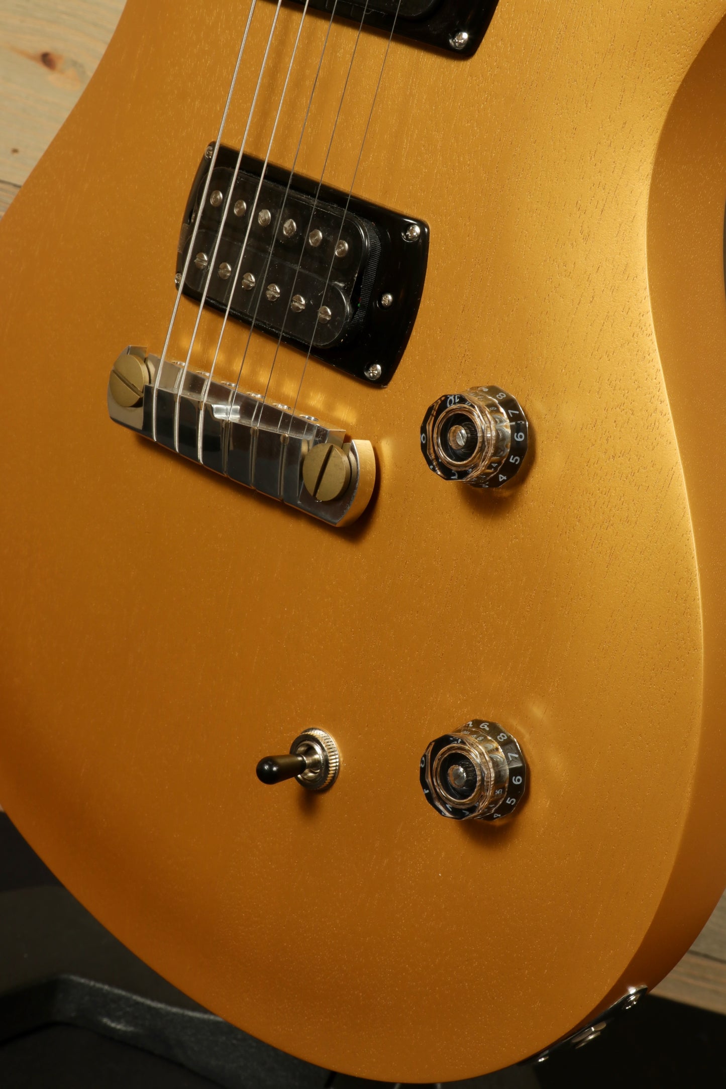 Close-up of the PRS SE CE24 Standard Stoptail guitar featuring a gold finish and control knobs