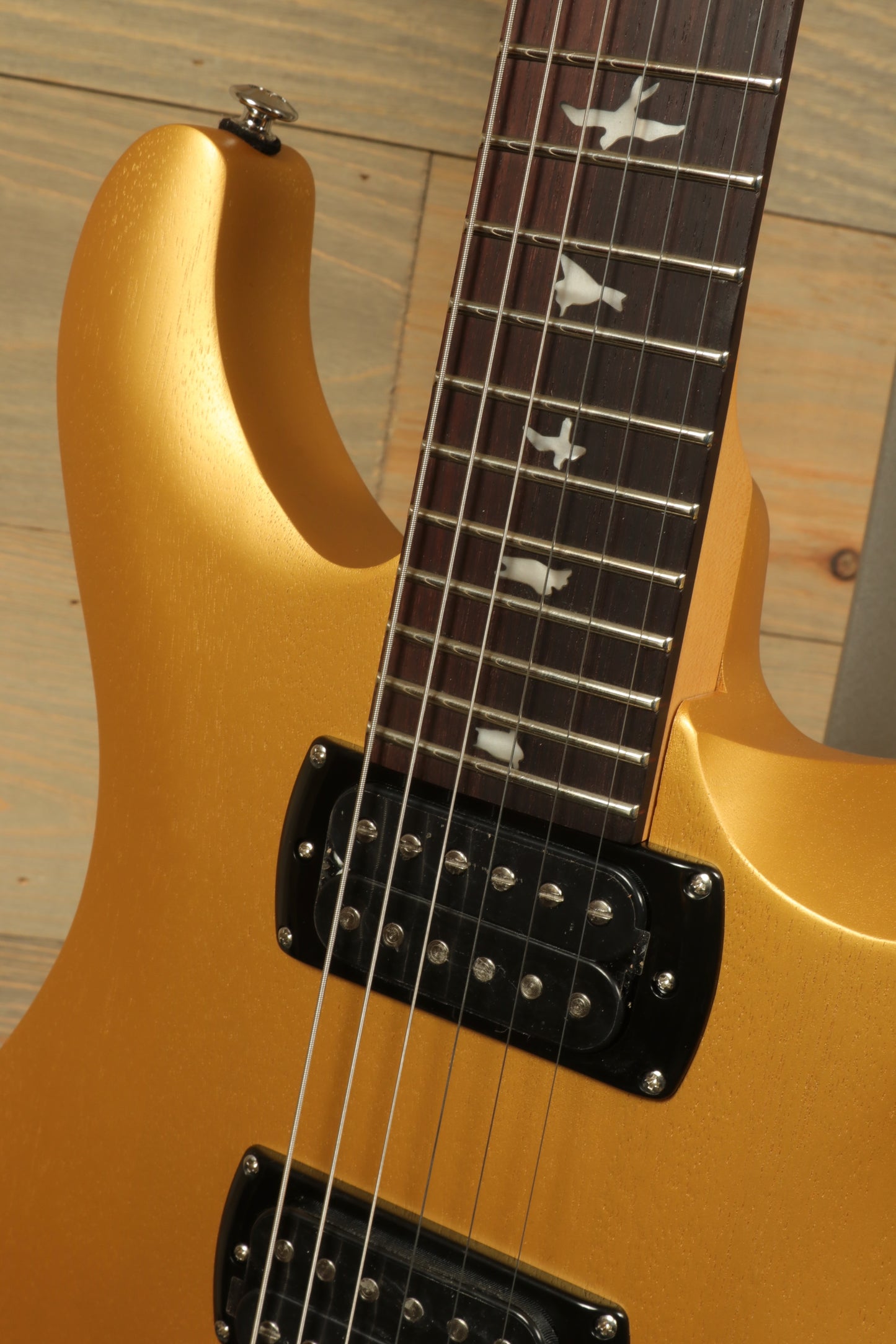 PRS SE CE24 Standard Stoptail guitar featuring a sleek gold finish and intricate fretboard inlays