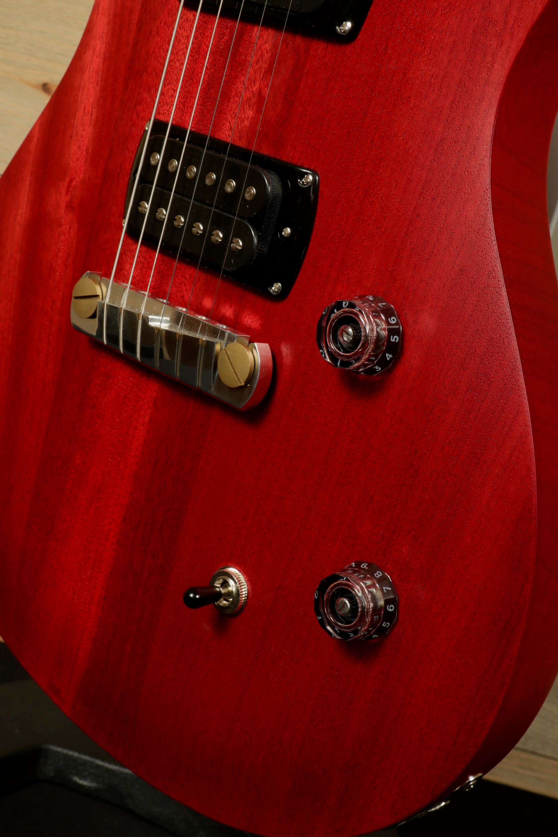 Close-up of PRS SE CE24 Standard Stoptail guitar showing the rich red finish and control knobs