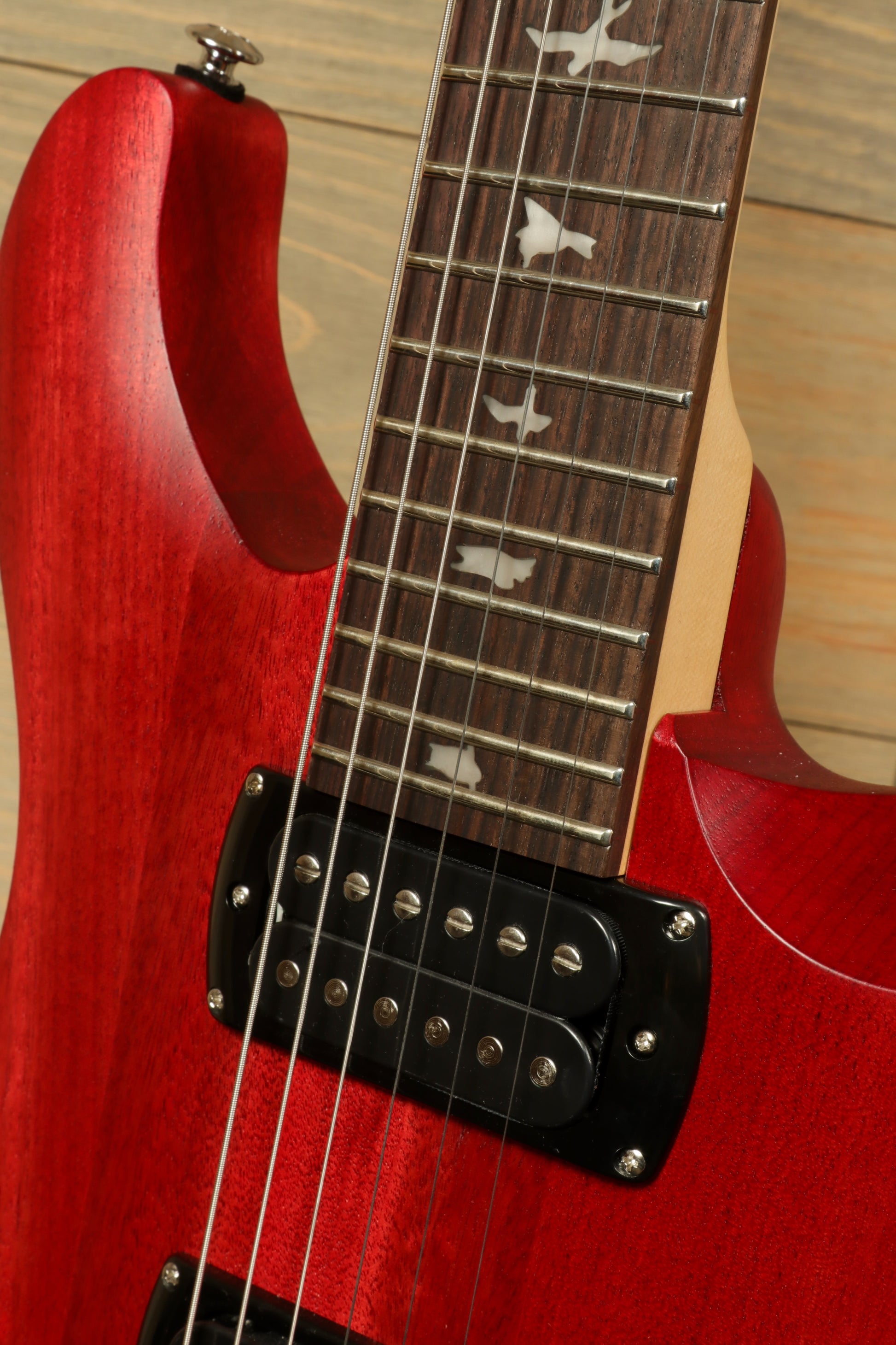 Close-up of PRS SE CE24 Standard Stoptail guitar with a beautiful red finish and intricate fretboard inlays