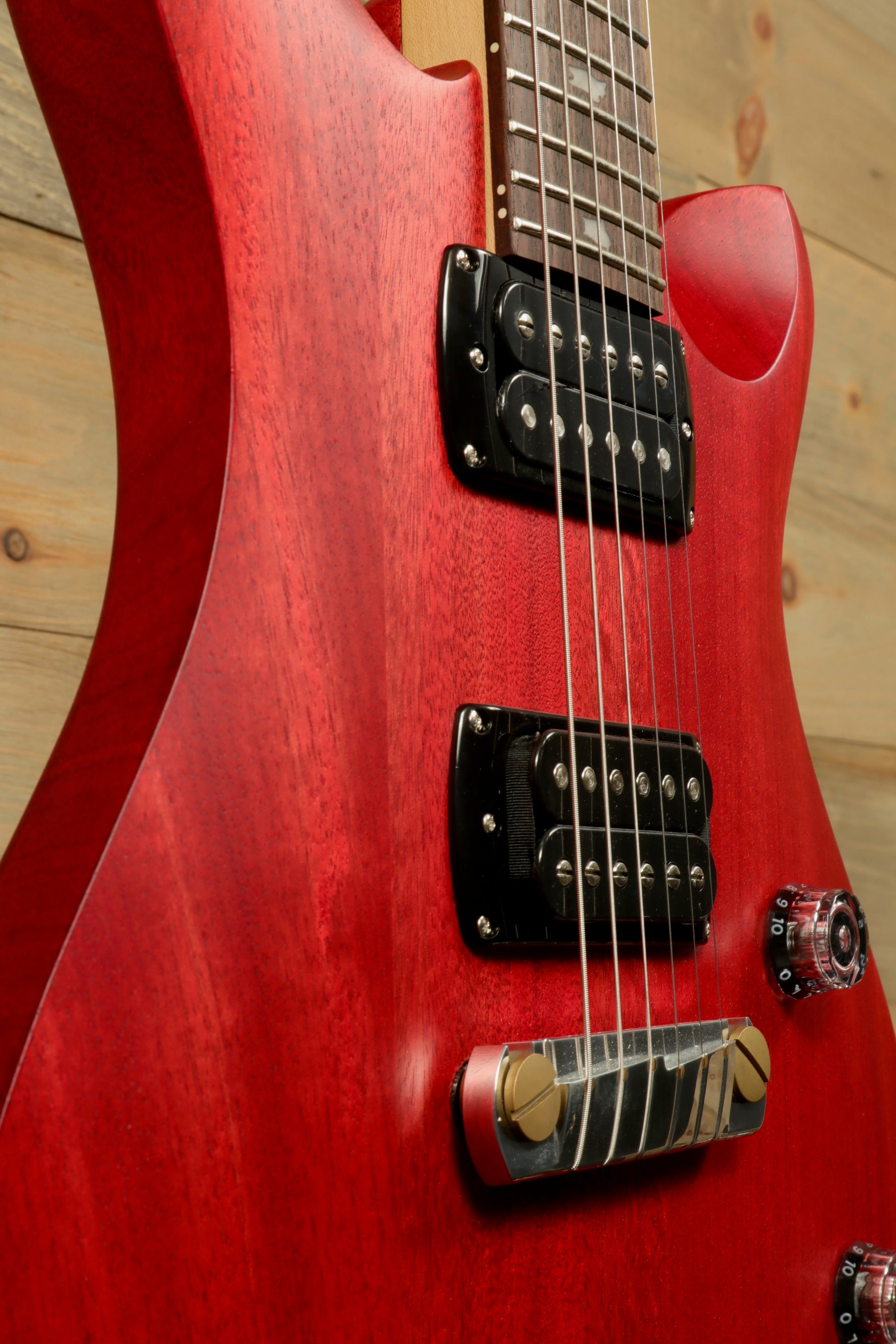 Close-up of PRS SE CE24 Standard Stoptail guitar in red with humbucker pickups