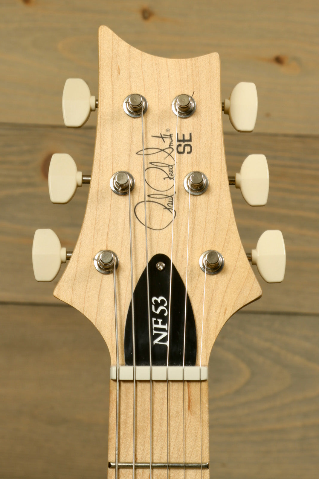 PRS SE NF53 guitar headstock in natural wood finish, top view showing tuning pegs and signature.