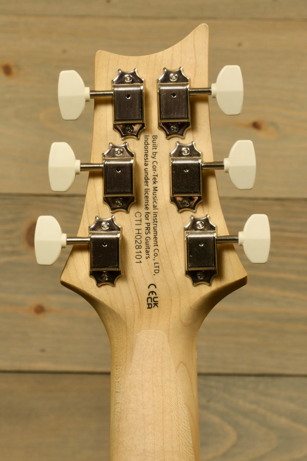 PRS SE NF53 guitar headstock with white tuning pegs, back view on natural wood finish