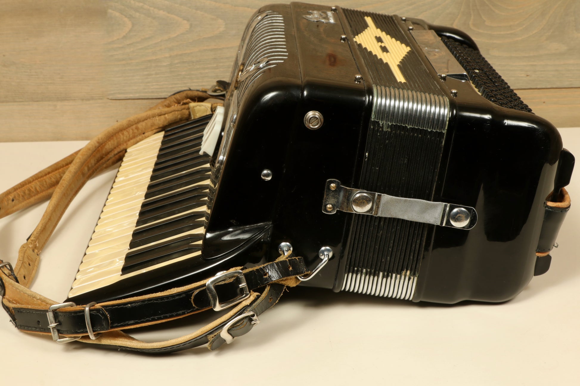Rivoli Little Maestro Accordion in black with ivory keys, side view showcasing straps and body design