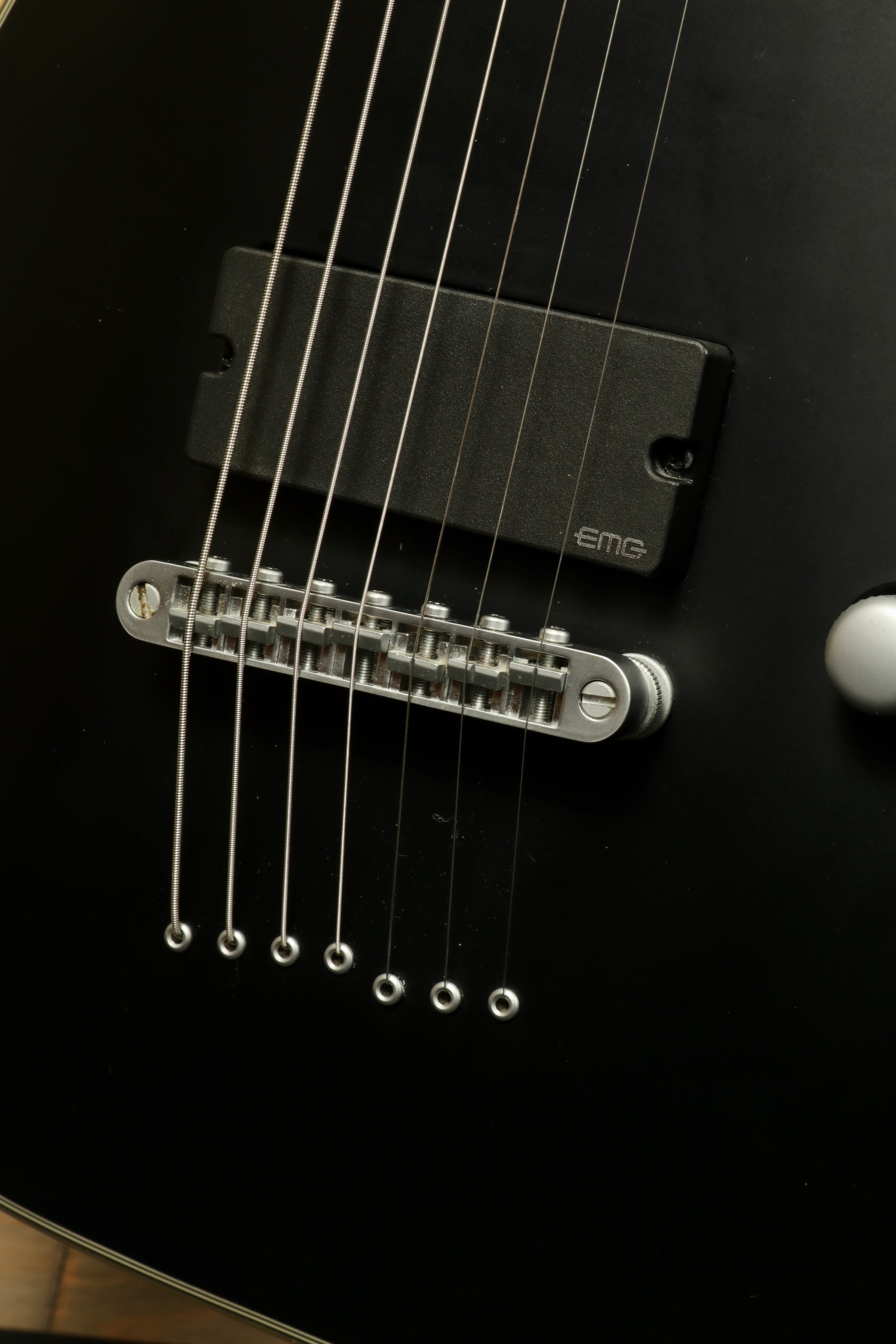 Close-up of used Schecter Damien 7 Platinum guitar showing EMG pickup and strings