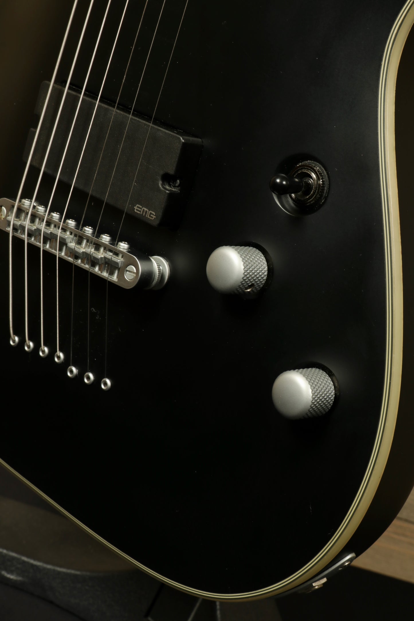 Close-up of used Schecter Damien 7 Platinum guitar showing black finish and control knobs