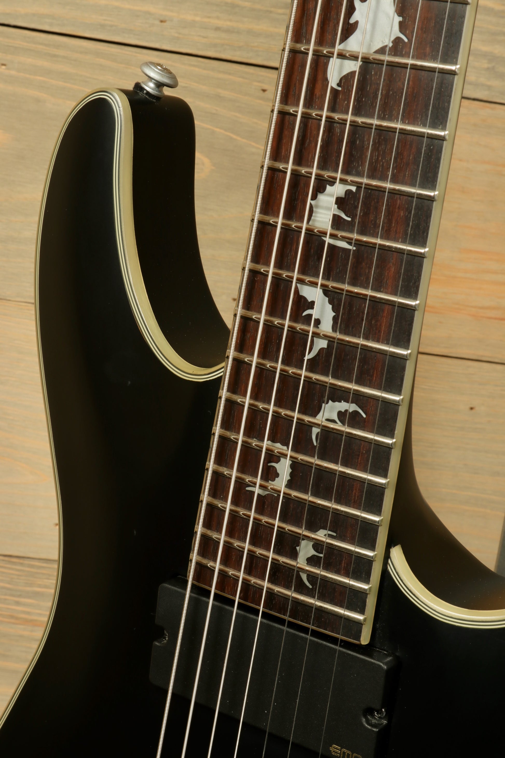 Used Schecter Damien 7 Platinum guitar with sleek black finish and intricate inlays on the fretboard