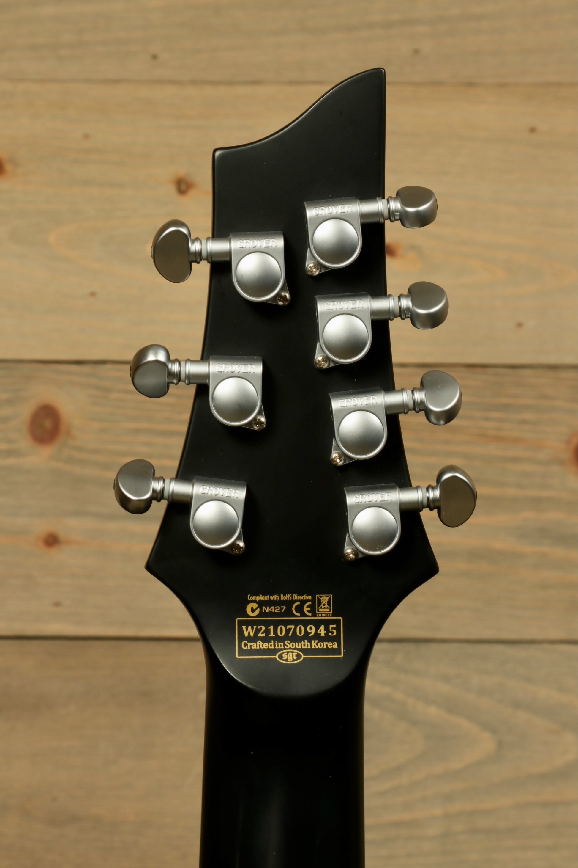 Back view of a used Schecter Damien 7 Platinum guitar showcasing tuning pegs and neck design