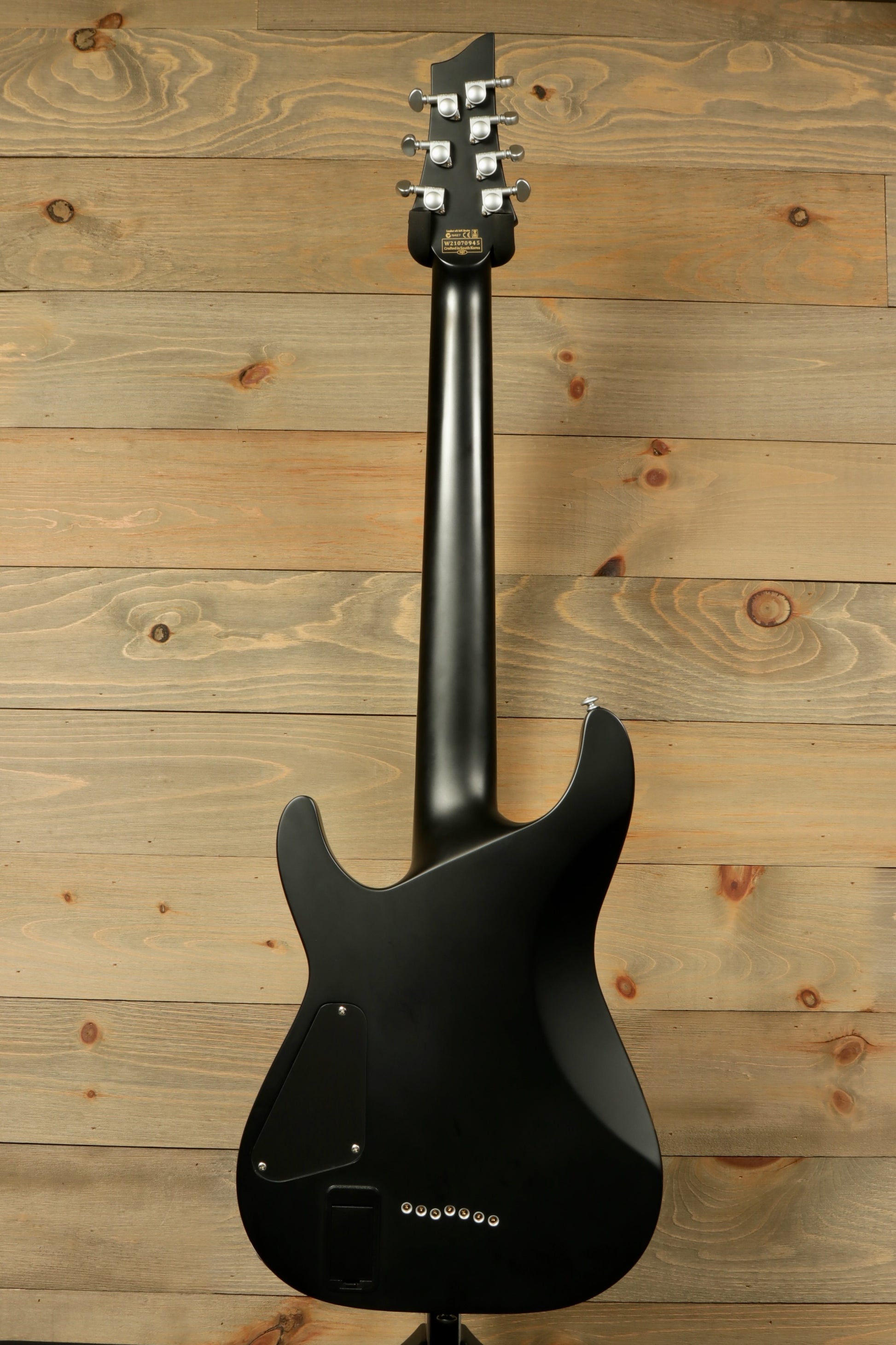 Back view of a used Schecter Damien 7 Platinum guitar showcasing its sleek black finish and solid body design