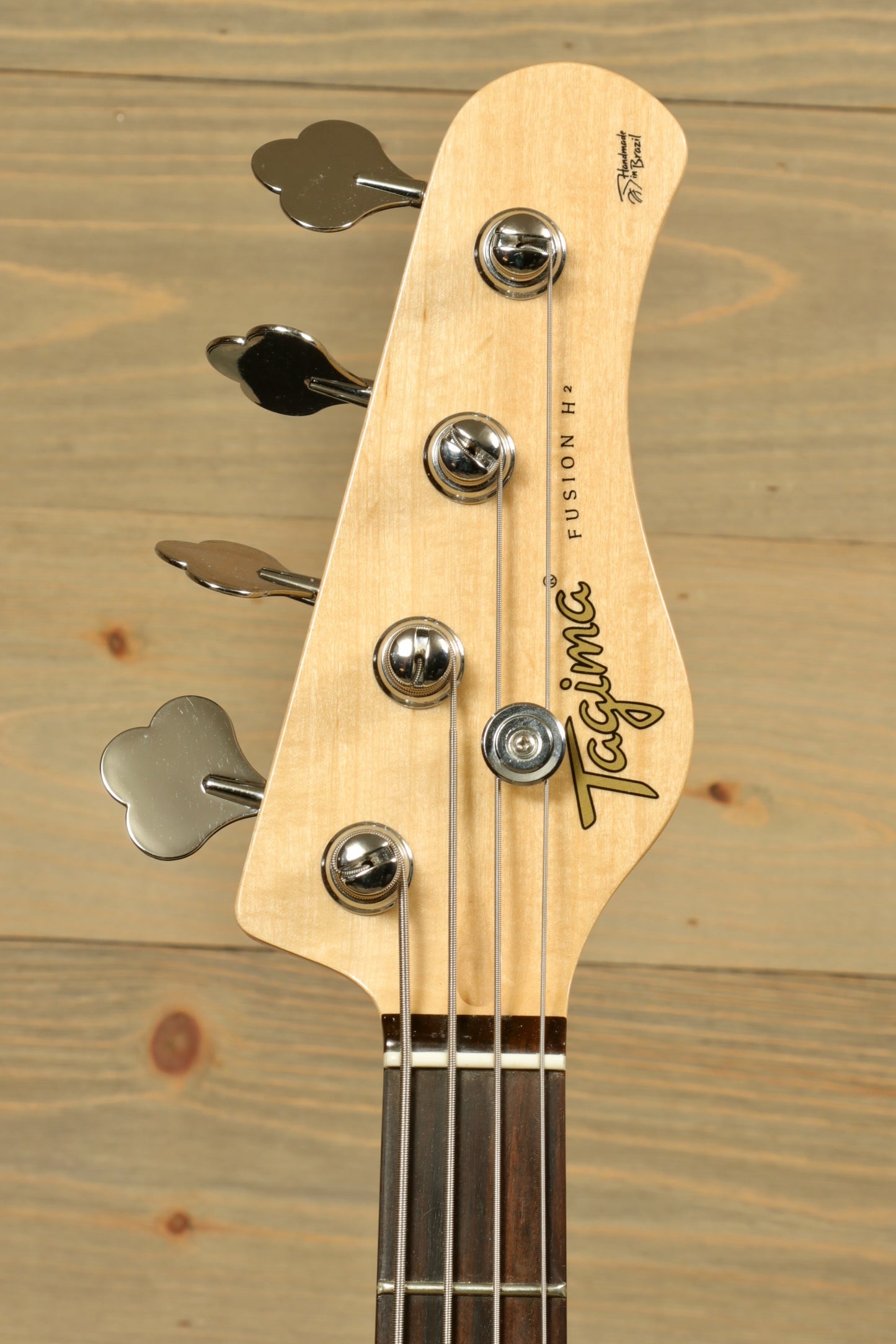 Tagima Fusion-4 H2 bass guitar headstock with chrome tuning pegs and a natural wood finish
