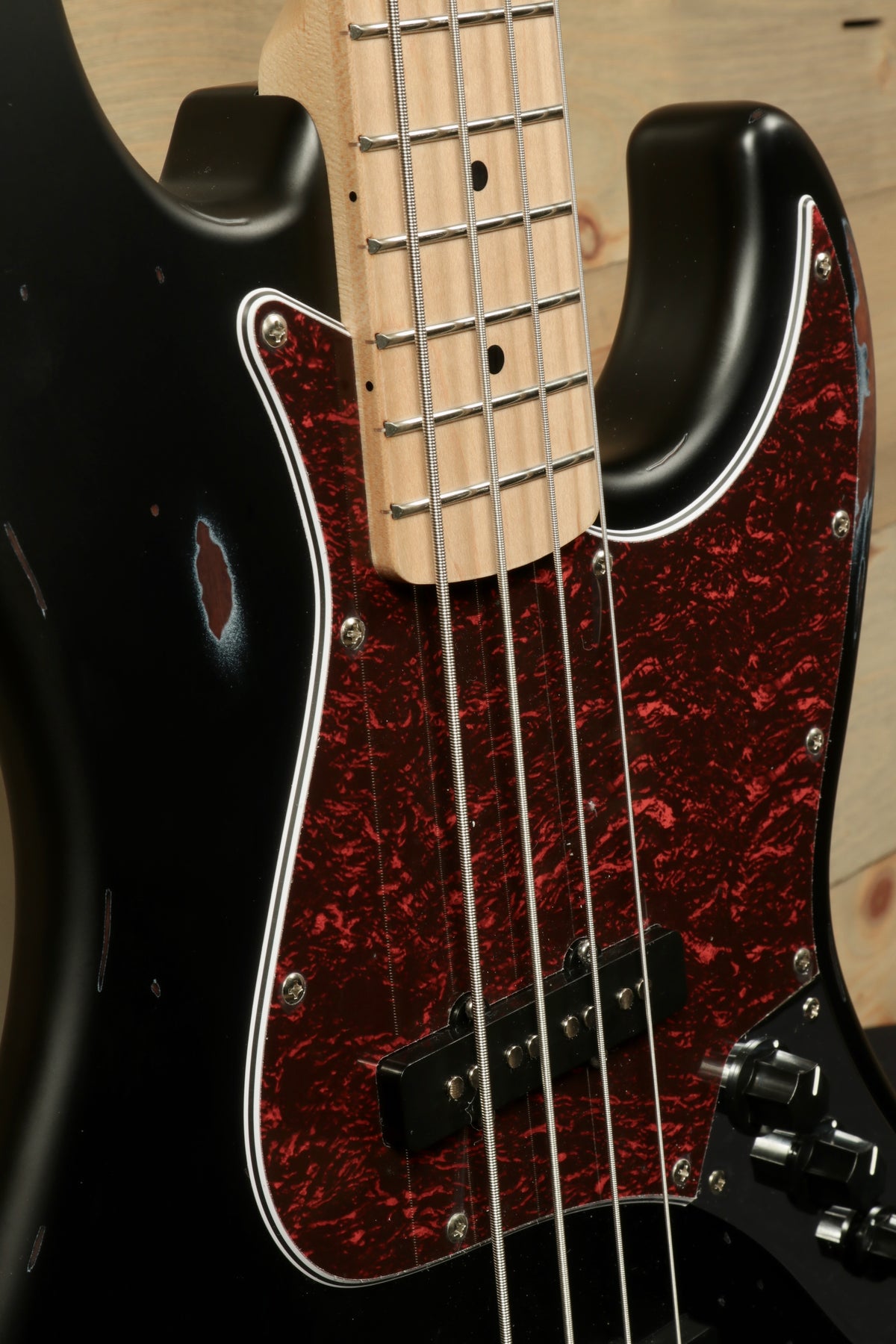 Tagima TBA-73 Electric Bass in black with a red pickguard, close-up view of body and neck