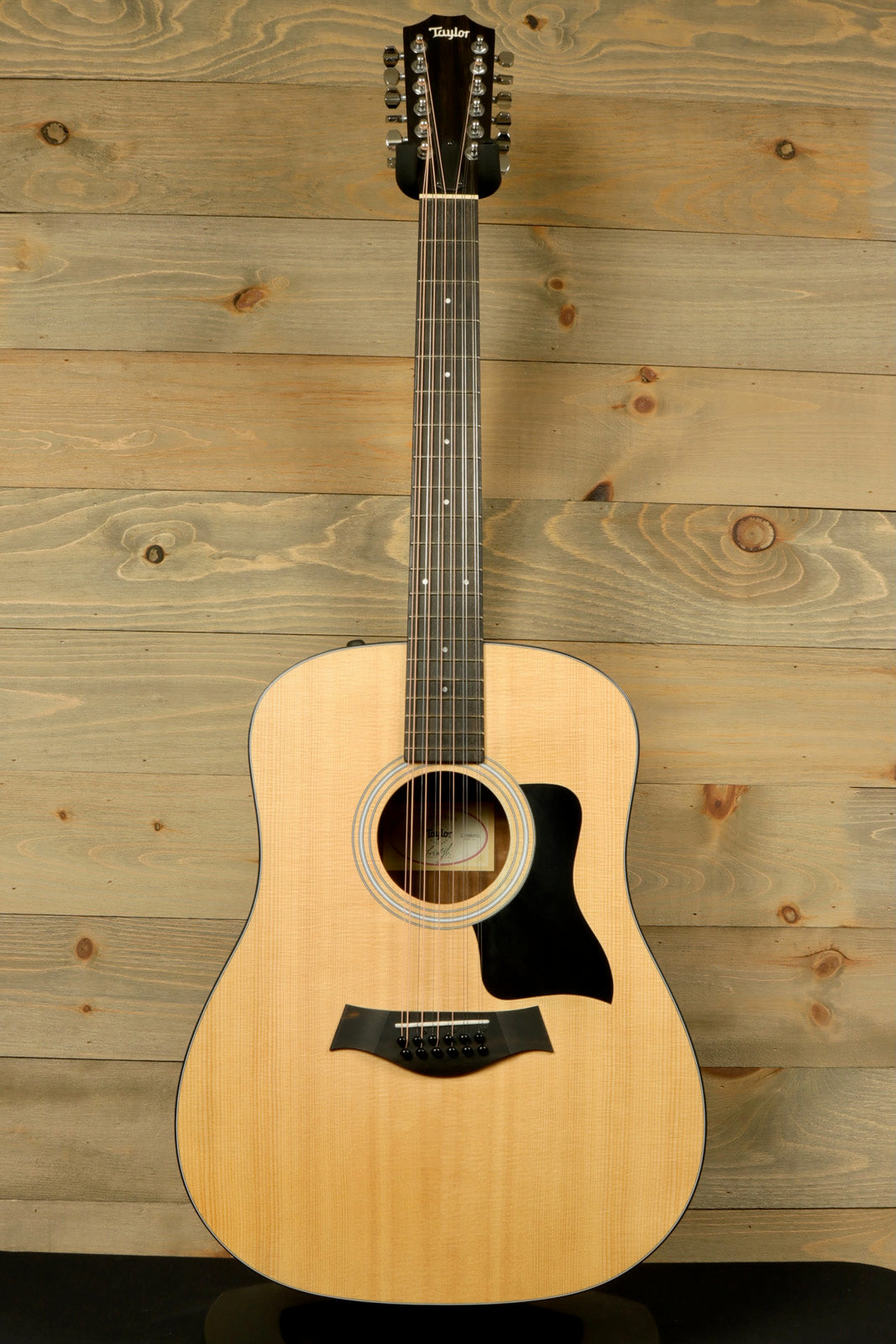 Taylor 150e - USED acoustic electric guitar with natural finish, front view on wooden background