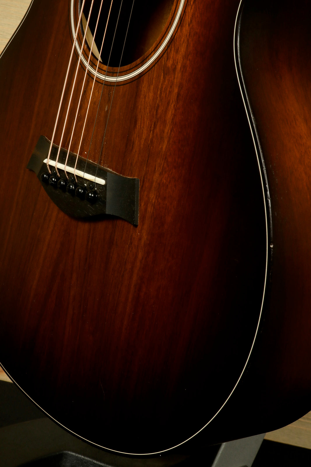 Taylor GS Mini-e Koa acoustic electric guitar, dark wood finish, close-up view of the body