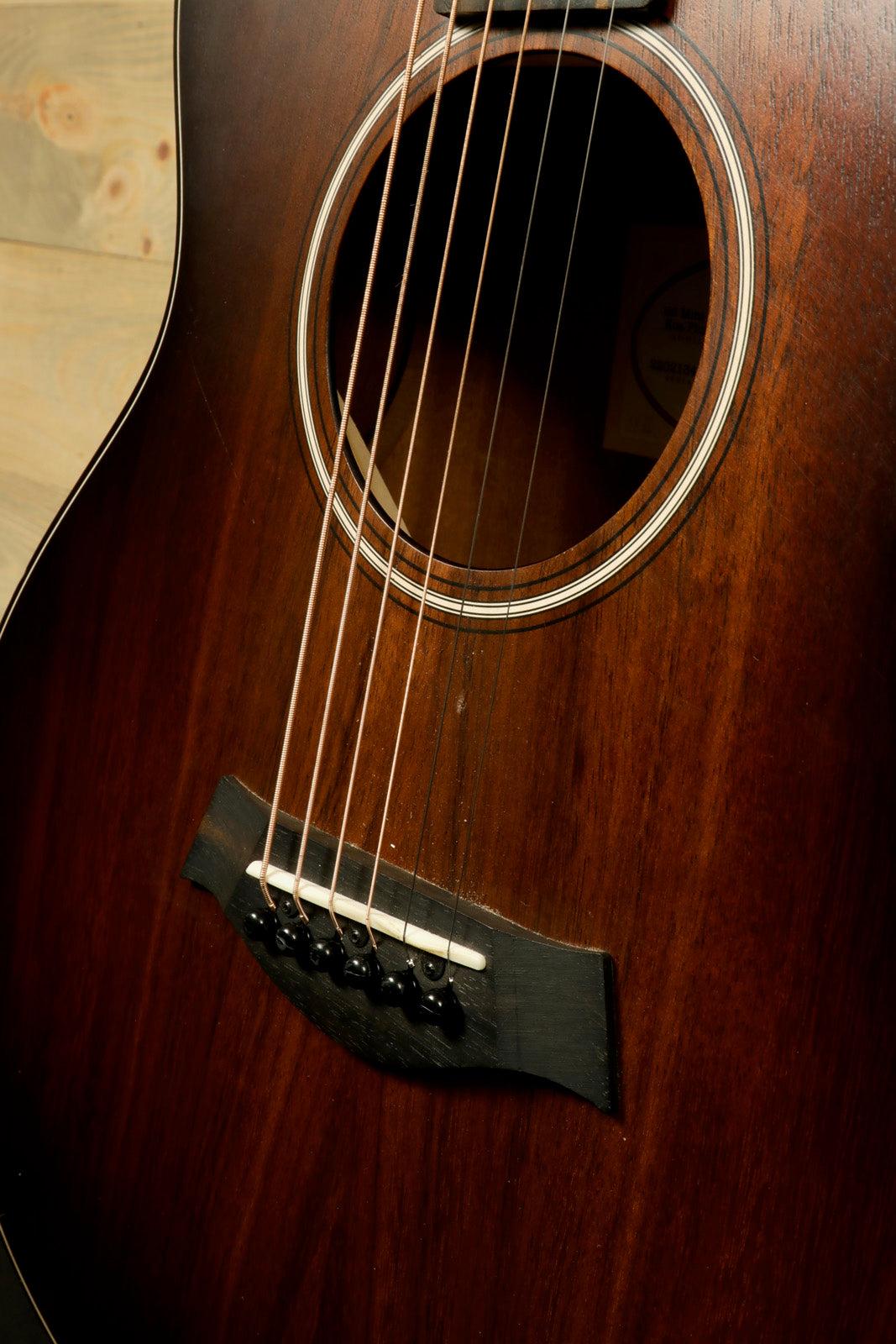 Taylor GS Mini-e Koa acoustic electric guitar, rich wood finish, angled view showcasing the soundhole and bridge