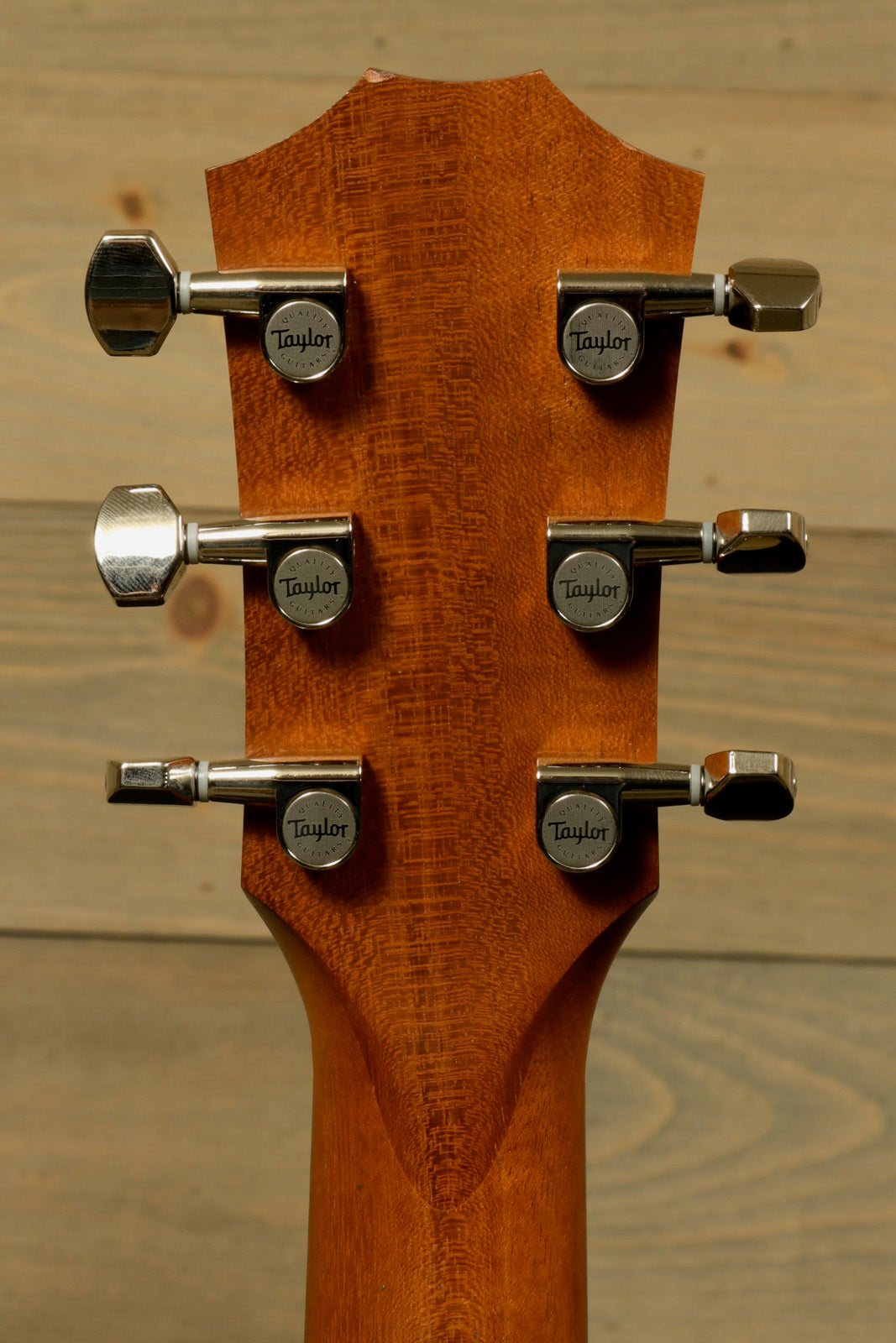 Taylor GS Mini-e Koa guitar headstock with chrome tuning pegs and rich wood grain finish