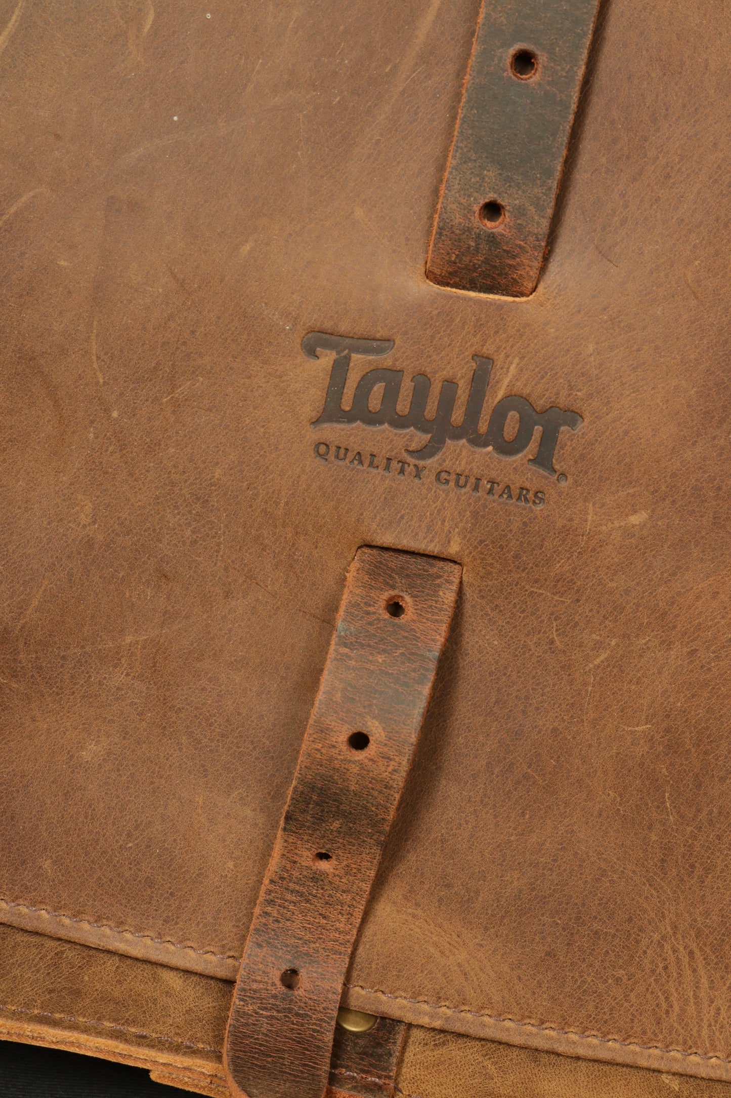 Close-up of Taylor Guitars messenger bag showcasing the embossed logo on premium leather