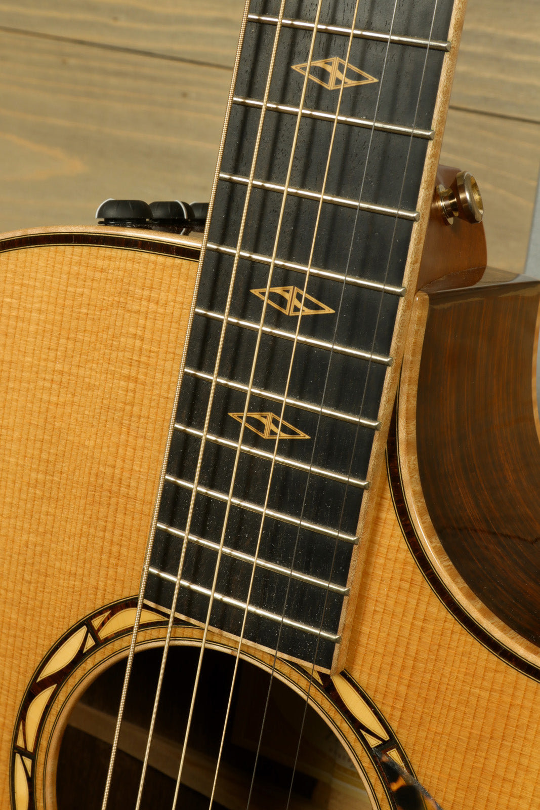 Close-up of the neck and fretboard of a used Taylor Cocobolo GA LTD guitar with intricate inlays.